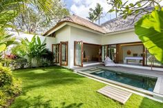 a house with a swimming pool in the middle of grass and palm trees around it