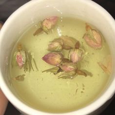 a white bowl filled with green liquid and flowers