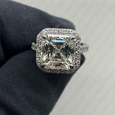 a fancy ring with an emerald cut diamond surrounded by pave and diamonds on top