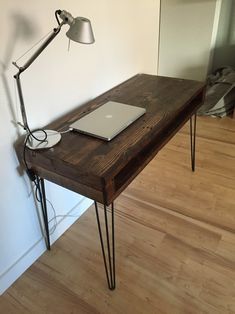 a laptop computer sitting on top of a wooden desk next to a light and lamp