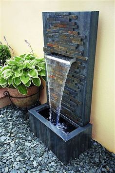 a water fountain is shown in front of a potted plant