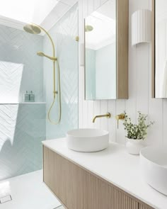 a bathroom with two sinks and a large mirror above it, along with a walk in shower