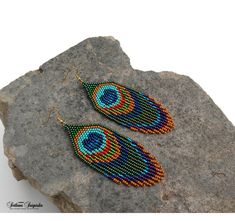 two pairs of beaded earrings sitting on top of a rock