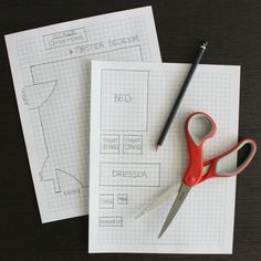 two pairs of red scissors sitting on top of paper next to some pens and pencils