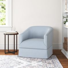 a blue chair sitting on top of a wooden floor next to a white book shelf