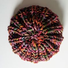 a ball of multicolored yarn sitting on top of a white table next to a wall