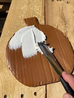 a person cutting into a piece of cake on top of a wooden table with a pair of scissors