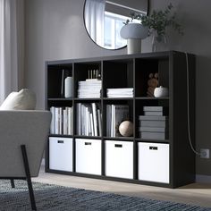 a living room with a chair, mirror and bookshelf