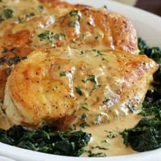 some chicken and spinach on a white plate with gravy in the middle