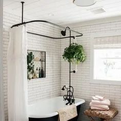 a bath tub sitting next to a white brick wall with potted plants on it