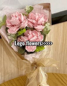 a bouquet of pink flowers sitting on top of a wooden table with the words lego flowers