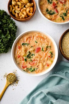 three bowls filled with different types of food on top of a white surface next to two spoons