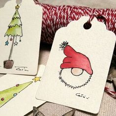 three tags with christmas designs on them sitting next to some scissors and other items in front of a pillow