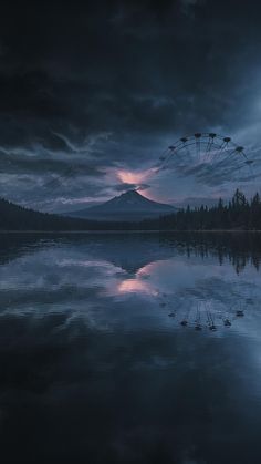 a ferris wheel sitting in the middle of a lake under a cloudy sky with dark clouds