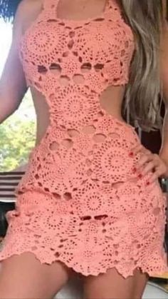 a woman wearing a pink crochet dress with cutouts on the bottom and sides