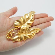 100% authentic gorgeous vintage Kenzo brooch with double-leaf motif in goldtone metal, signed Kenzo at the backBrand: KenzoColor: Gold-toneMaterial: Gold-tone metalCondition: Excellent condition Measurements: Width 6 cm x Height 8.5 cmAccessories: NoneCondition Rankings:Mint - Perfect condition and presents as brand new. No indication of handling or marks.Excellent - Nearly mint condition with only very minor evidence of handling.Very Good - Evidence of handling with no major flaws or wear.Good Vintage Gold Leaf Jewelry, Gold Leaf Brooch For Gift, Unique Jewelry Vintage, Luxury Art Nouveau Hallmarked Brooch, Vintage Gold Leaf-shaped Jewelry, Art Nouveau Yellow Gold Brooch, Vintage Gold Necklace, Swarovski Brooch, Vintage Yellow Gold Baroque Brooch