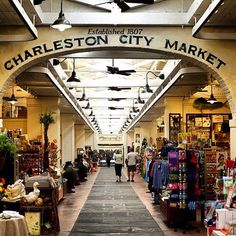 the entrance to charleston city market with people walking through it and lots of items on display