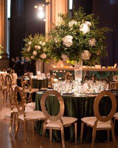 the tables are set up for a formal function with green linens and gold chairs