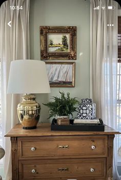 a dresser with a lamp and pictures on the wall