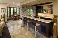 a living room filled with lots of furniture and a stone wall behind the bar area