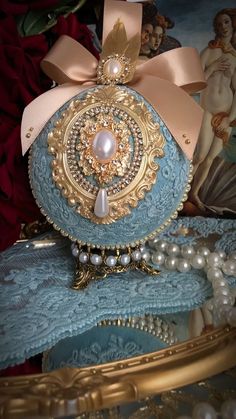 a blue purse with pearls and a pink bow on it's head sitting on top of a table