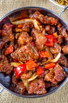 a bowl filled with meat and vegetables on top of a table next to some noodles