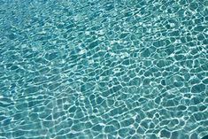 water ripples over the surface of a swimming pool with clear blue water and sunlight reflecting on it