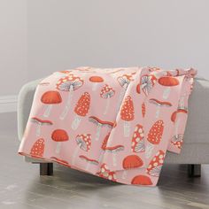 a pink blanket with mushrooms on it is sitting on a chair in front of a couch