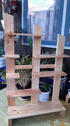 a wooden shelf sitting on top of a table next to a potted plant