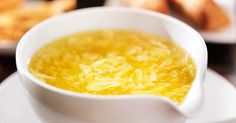 a white bowl filled with soup on top of a plate next to other plates and bread