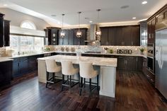 a large kitchen with dark wood floors and white counter tops is pictured in this image