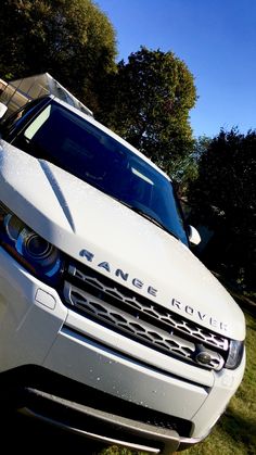 a range rover parked in the grass next to some trees