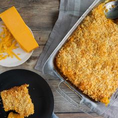 a casserole dish with cheese on top next to a plate and spoons