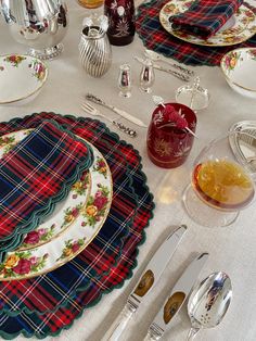 a table set with place settings, silverware and plaid napkins on top of it