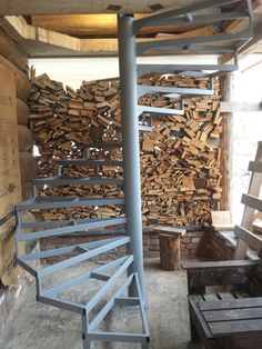 there is a spiral staircase made out of firewood in the room with many pieces of wood stacked on it