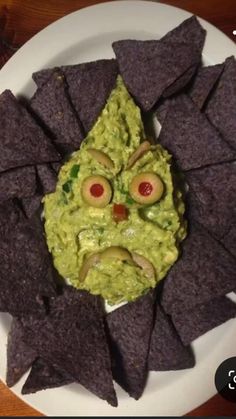 a white plate topped with chips and guacamole covered in an evil face