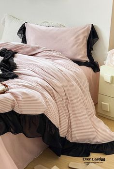 a bed with pink and black comforter in a bedroom next to a white dresser