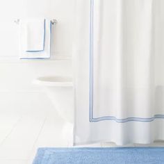 a bathroom with a blue rug and white shower curtain