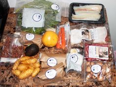 an assortment of food is displayed on a counter with plastic wrappers and other items