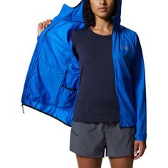 a woman wearing a blue jacket and gray shorts is holding her coat over her shoulder