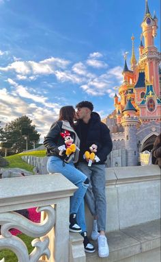 a man and woman kissing in front of a castle with mickey mouses on it