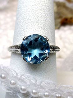 Natural Blue Topaz Art Deco RingButton Design#D12 This is an Art Deco reproduction ring in sterling silver. This vintage style ring is set with a stunning 3 carat natural gemstone. The round full cut gemstone is 10mm in diameter (3/8th"). The inside of the band is marked 925 for sterling silver. Notice the beautiful craftsmanship of the silver filigree setting. Tiny leaf filigree travel down each side of the band. The round stone sits on a swirled filigree setting. This ring is as cute as a butt Leaf Filigree, 1930's Style, Vintage Style Rings, Nature Ring, 1930s Fashion, Ring Art Deco, Button Ring, 3 Carat, Silver Filigree