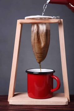 a person pouring coffee into a red cup