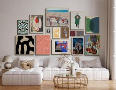 a living room filled with white furniture and lots of pictures on the wall above it