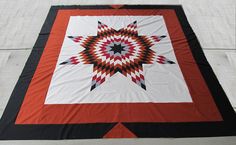 a red, black and white quilt with an intricate star design on the center piece