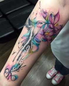 a woman's arm with watercolor tattoos on it and flowers in the middle