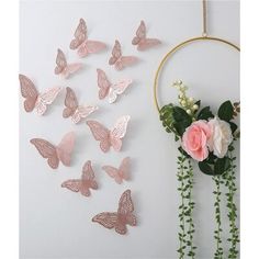 a bunch of pink butterflies hanging on the wall next to a vase with flowers in it