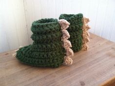 two crocheted green boots sitting on top of a wooden table next to each other