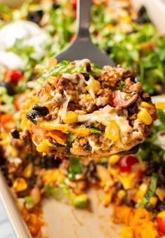 a spoon full of taco salad on top of a casserole dish