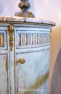 an ornate white cabinet with marble top and gold trimmings on the door handles